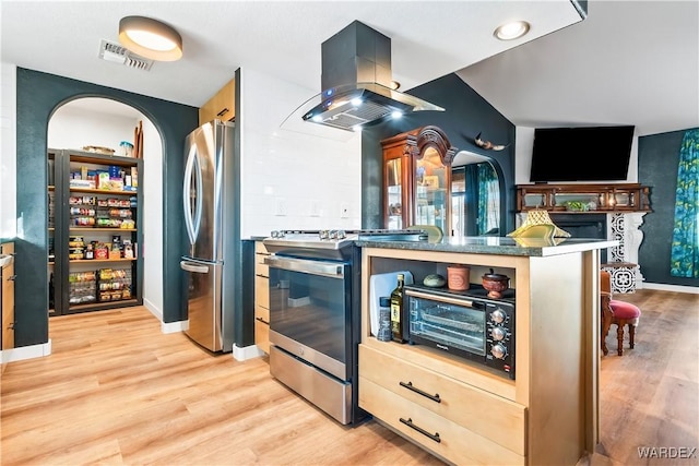 kitchen with visible vents, island exhaust hood, appliances with stainless steel finishes, and light wood-style flooring