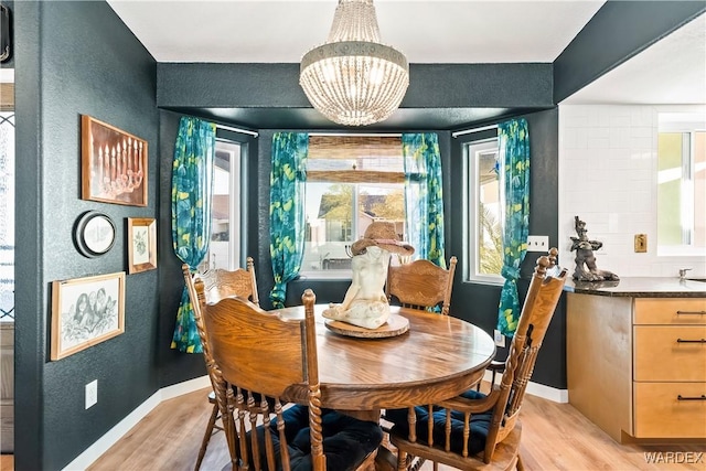 dining area featuring a chandelier, light wood-style flooring, and baseboards