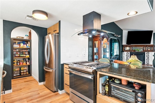 kitchen with island exhaust hood, light wood finished floors, stainless steel appliances, visible vents, and open floor plan