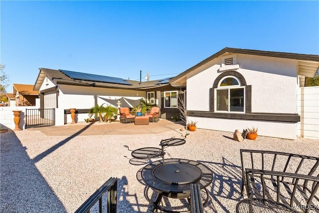 back of property with a patio, stucco siding, an outdoor hangout area, roof mounted solar panels, and fence