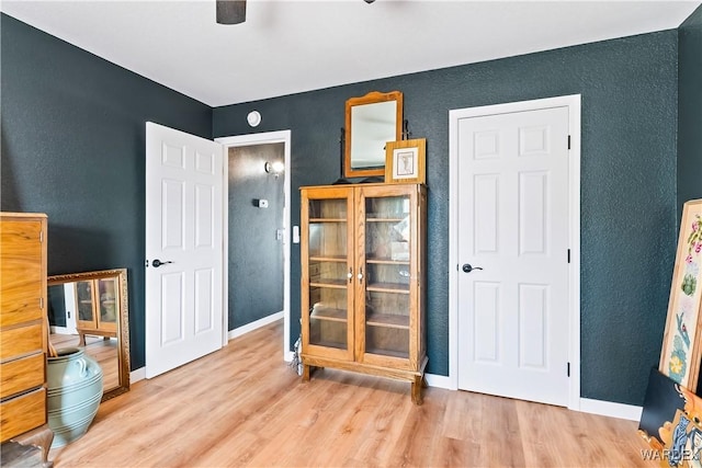 bedroom with light wood-type flooring, ceiling fan, and baseboards