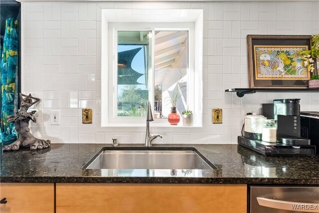 kitchen with dishwasher, tasteful backsplash, dark stone counters, and a sink