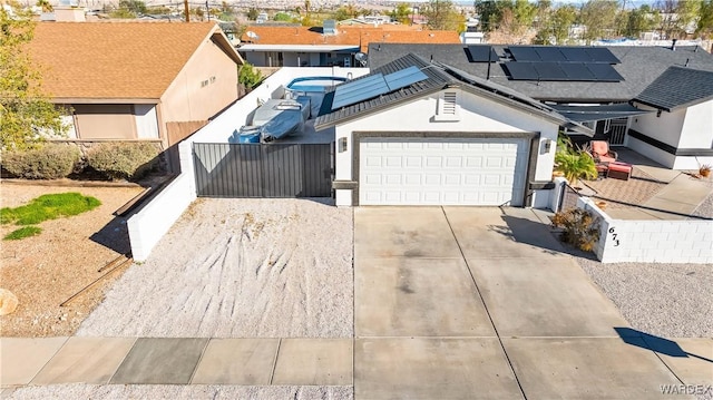 view of front of house featuring a garage, solar panels, concrete driveway, fence, and stucco siding