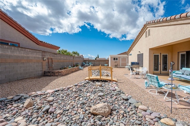 view of yard with an outbuilding, a patio, a storage shed, and a fenced backyard