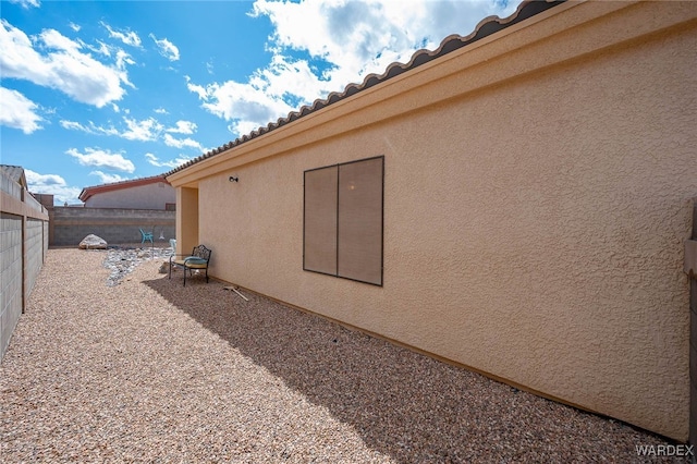 view of side of property with stucco siding, a patio, and a fenced backyard