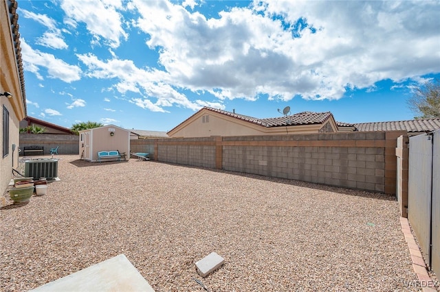 view of yard featuring a storage unit, cooling unit, an outbuilding, and a fenced backyard