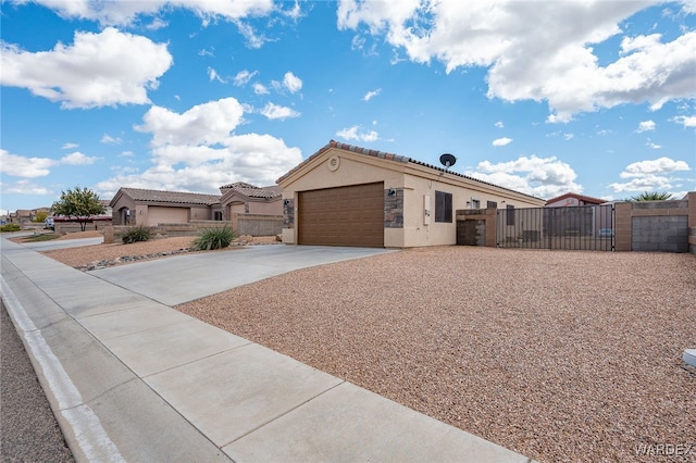 view of front of home with fence, stucco siding, a garage, driveway, and a gate