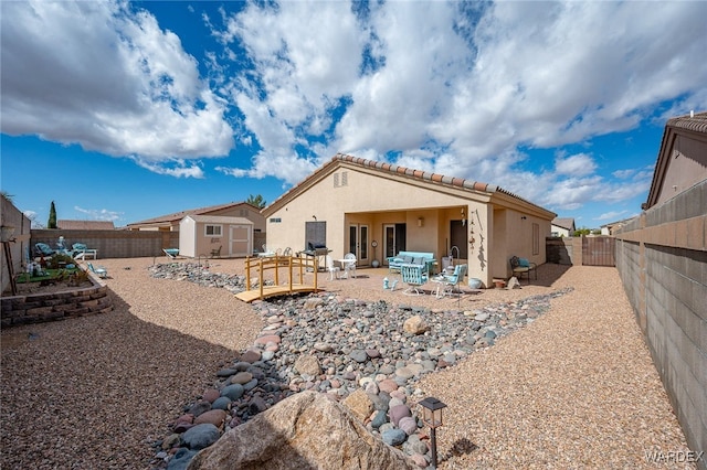 back of property featuring an outbuilding, stucco siding, a storage unit, and a fenced backyard