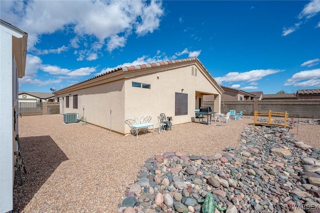 back of house with stucco siding, central air condition unit, a patio, and a fenced backyard