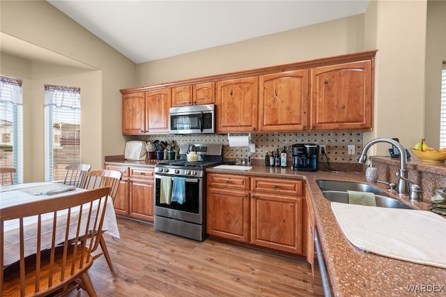 kitchen featuring stainless steel appliances, tasteful backsplash, brown cabinetry, and light wood finished floors