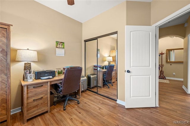 office area featuring light wood-type flooring, arched walkways, and baseboards