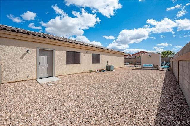 back of property featuring a fenced backyard, a storage shed, an outdoor structure, and stucco siding