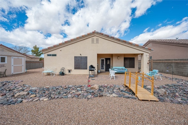 rear view of property with a patio area, stucco siding, an outdoor structure, and a fenced backyard