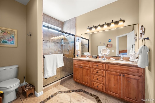 full bathroom with double vanity, a sink, a shower stall, tile patterned floors, and toilet