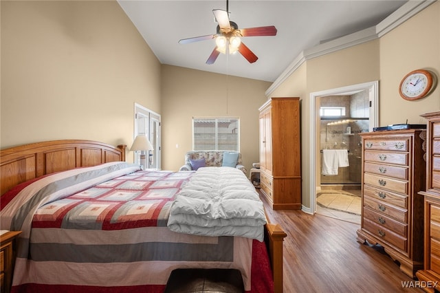 bedroom featuring connected bathroom, wood finished floors, a ceiling fan, and vaulted ceiling