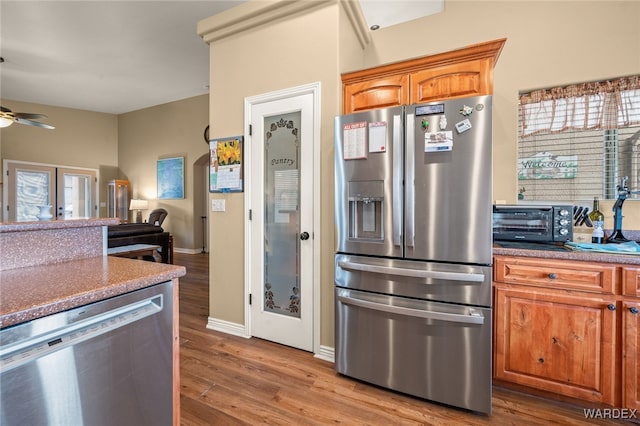 kitchen with ceiling fan, a toaster, brown cabinets, appliances with stainless steel finishes, and wood finished floors