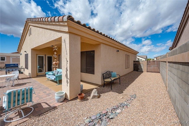 rear view of property featuring stucco siding, a ceiling fan, a gate, a patio, and fence