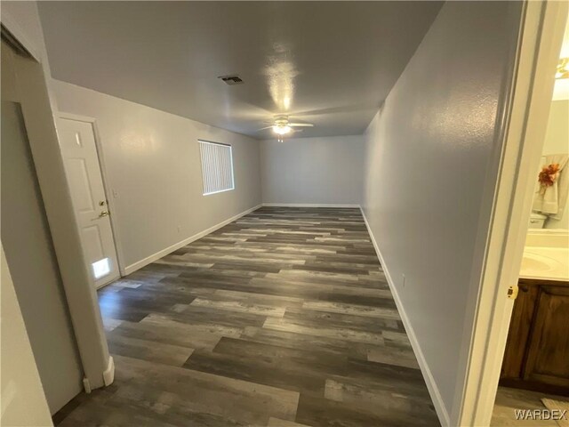 spare room with a ceiling fan, visible vents, baseboards, and wood finished floors