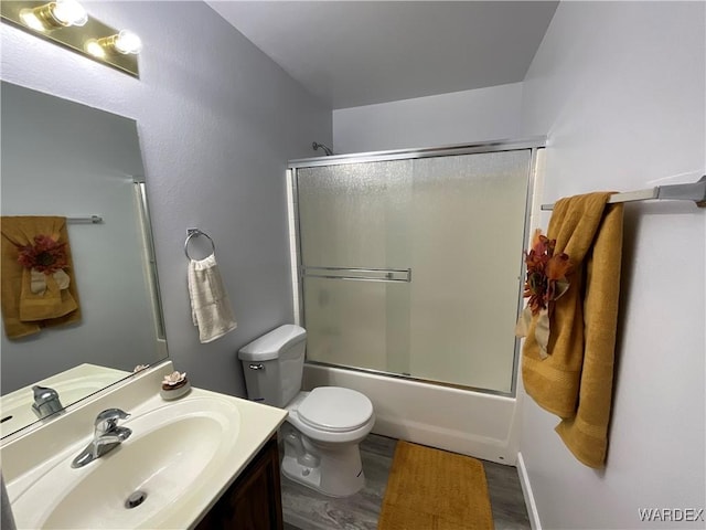 bathroom featuring combined bath / shower with glass door, vanity, toilet, and wood finished floors