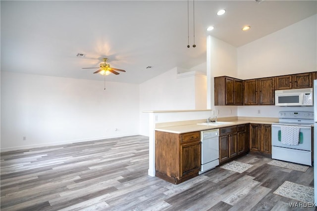 kitchen with light wood finished floors, light countertops, open floor plan, a sink, and white appliances