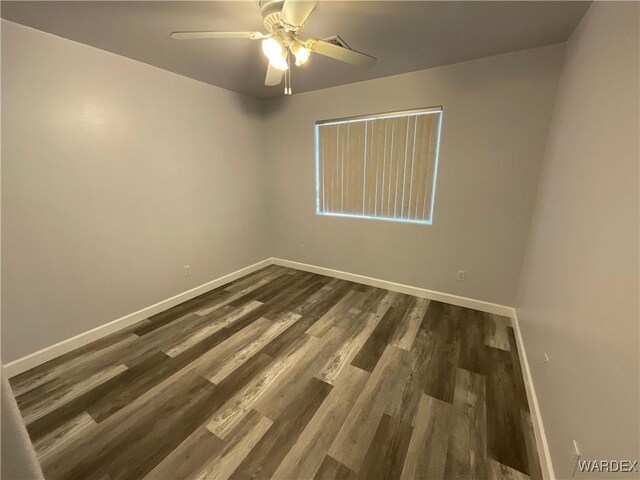 empty room with dark wood-style floors, baseboards, and a ceiling fan