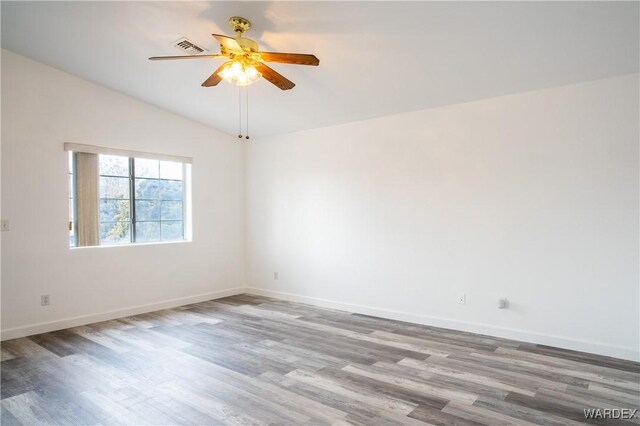 unfurnished room with ceiling fan, wood finished floors, visible vents, baseboards, and vaulted ceiling