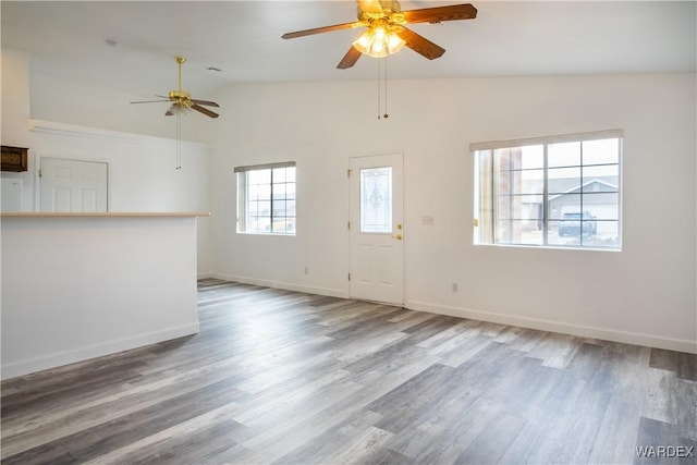 unfurnished living room with lofted ceiling, ceiling fan, wood finished floors, and baseboards