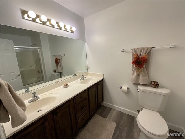 full bathroom featuring double vanity, a sink, toilet, and wood finished floors