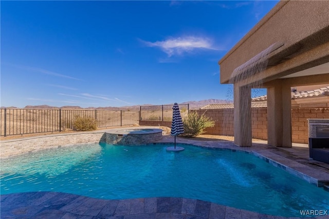 view of swimming pool featuring a fenced backyard, a pool with connected hot tub, and a mountain view