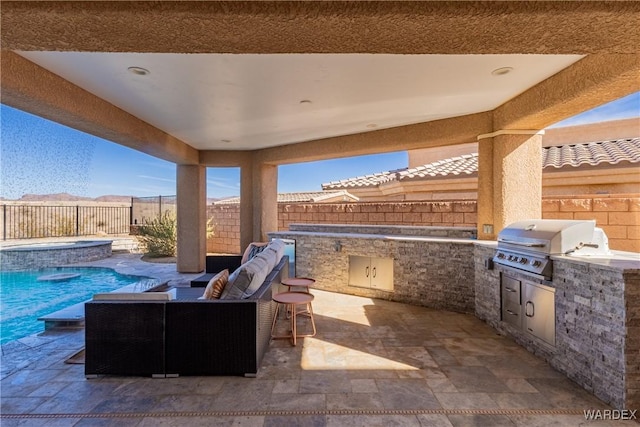 view of patio / terrace with a grill, an outdoor kitchen, a fenced backyard, and an in ground hot tub