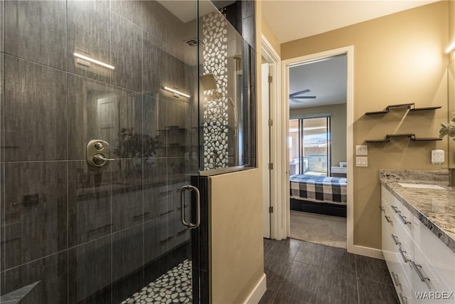 full bathroom featuring vanity, a shower stall, baseboards, and ensuite bathroom