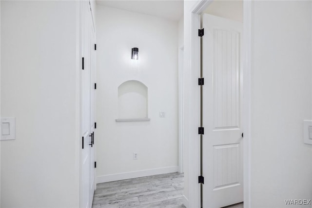 hall with light wood-style flooring and baseboards