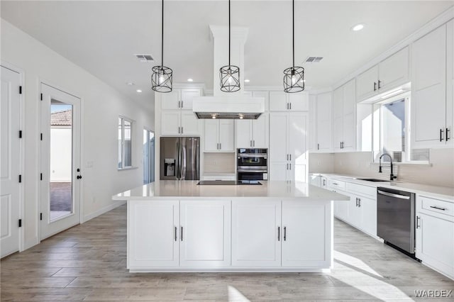 kitchen with a kitchen island, appliances with stainless steel finishes, light countertops, and pendant lighting