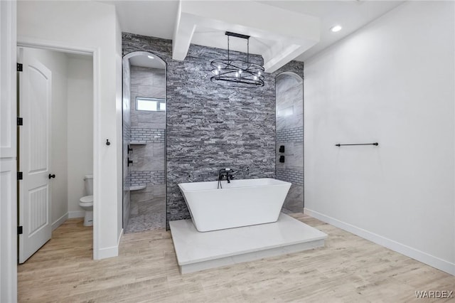 full bathroom with toilet, a soaking tub, baseboards, and wood finished floors