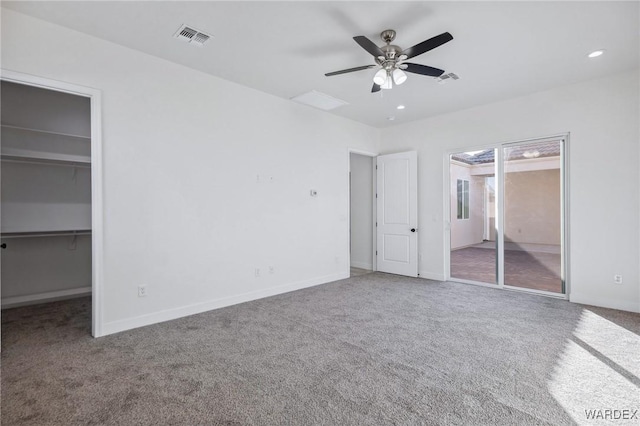 unfurnished bedroom featuring a walk in closet, a closet, visible vents, and carpet