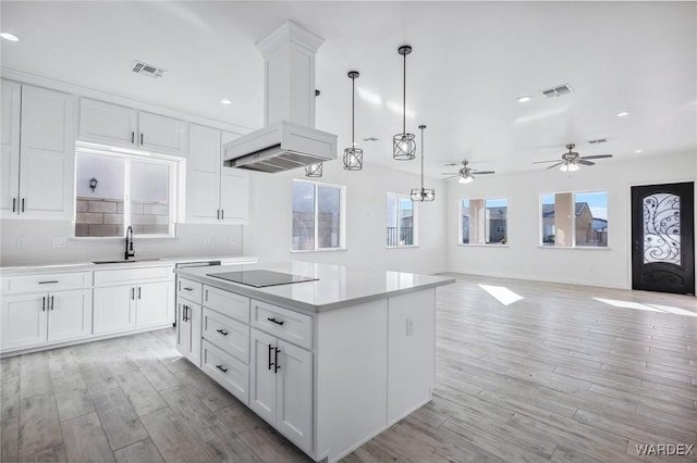 kitchen with white cabinets, visible vents, a kitchen island, and black electric cooktop