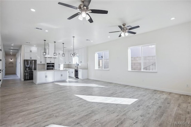 unfurnished living room featuring baseboards, light wood-style flooring, visible vents, and recessed lighting