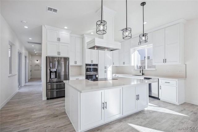 kitchen with stainless steel appliances, light countertops, hanging light fixtures, white cabinets, and a kitchen island