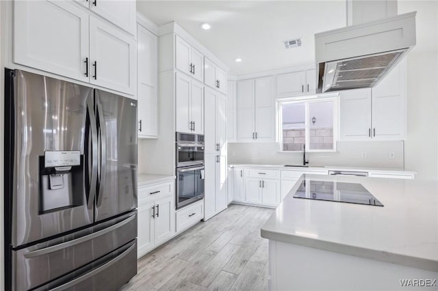 kitchen featuring visible vents, appliances with stainless steel finishes, light wood-style floors, white cabinetry, and a sink