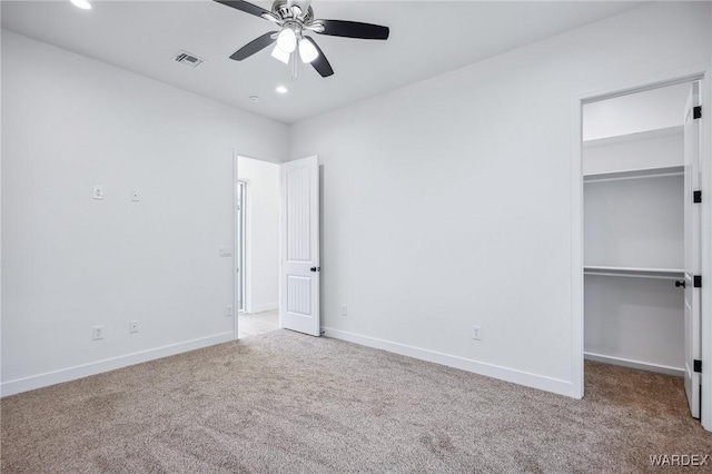 unfurnished bedroom with carpet, visible vents, and a walk in closet