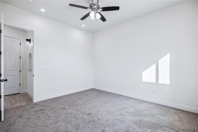 empty room with a ceiling fan, baseboards, arched walkways, and carpet flooring