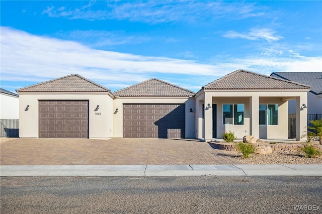 view of front of property with a garage, driveway, a tile roof, and stucco siding