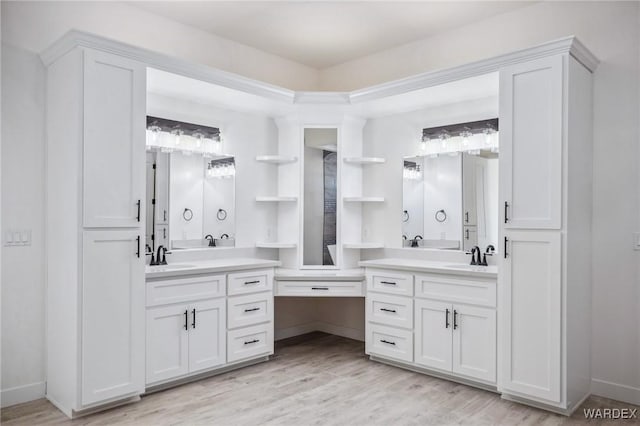 full bathroom with a sink, two vanities, wood finished floors, and baseboards