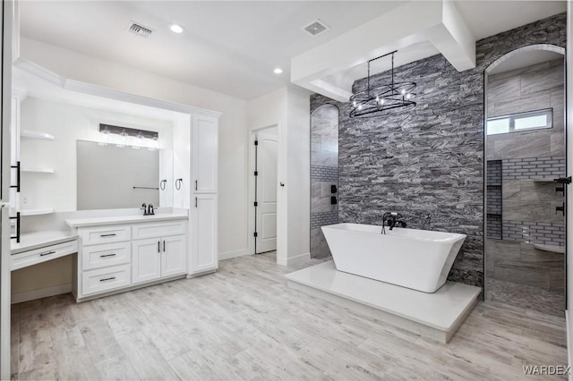 bathroom featuring visible vents, a soaking tub, wood finished floors, vanity, and a walk in shower