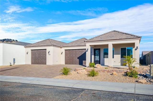 view of front of property with a garage, decorative driveway, a tile roof, and stucco siding