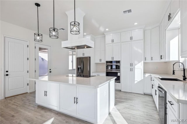 kitchen with stainless steel appliances, white cabinets, light countertops, hanging light fixtures, and a center island