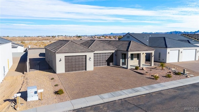 view of front facade featuring an attached garage, a mountain view, a tile roof, driveway, and stucco siding