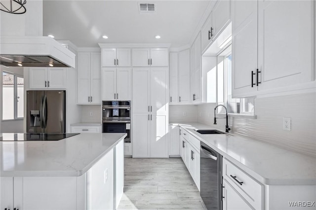 kitchen featuring visible vents, appliances with stainless steel finishes, premium range hood, white cabinetry, and a sink