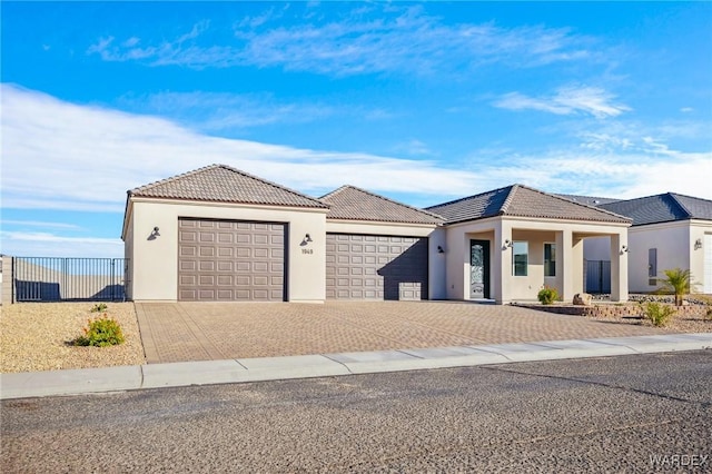 view of front of house featuring stucco siding, an attached garage, fence, driveway, and a tiled roof