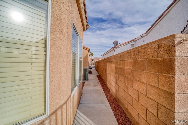 view of home's exterior featuring fence, central AC unit, and stucco siding